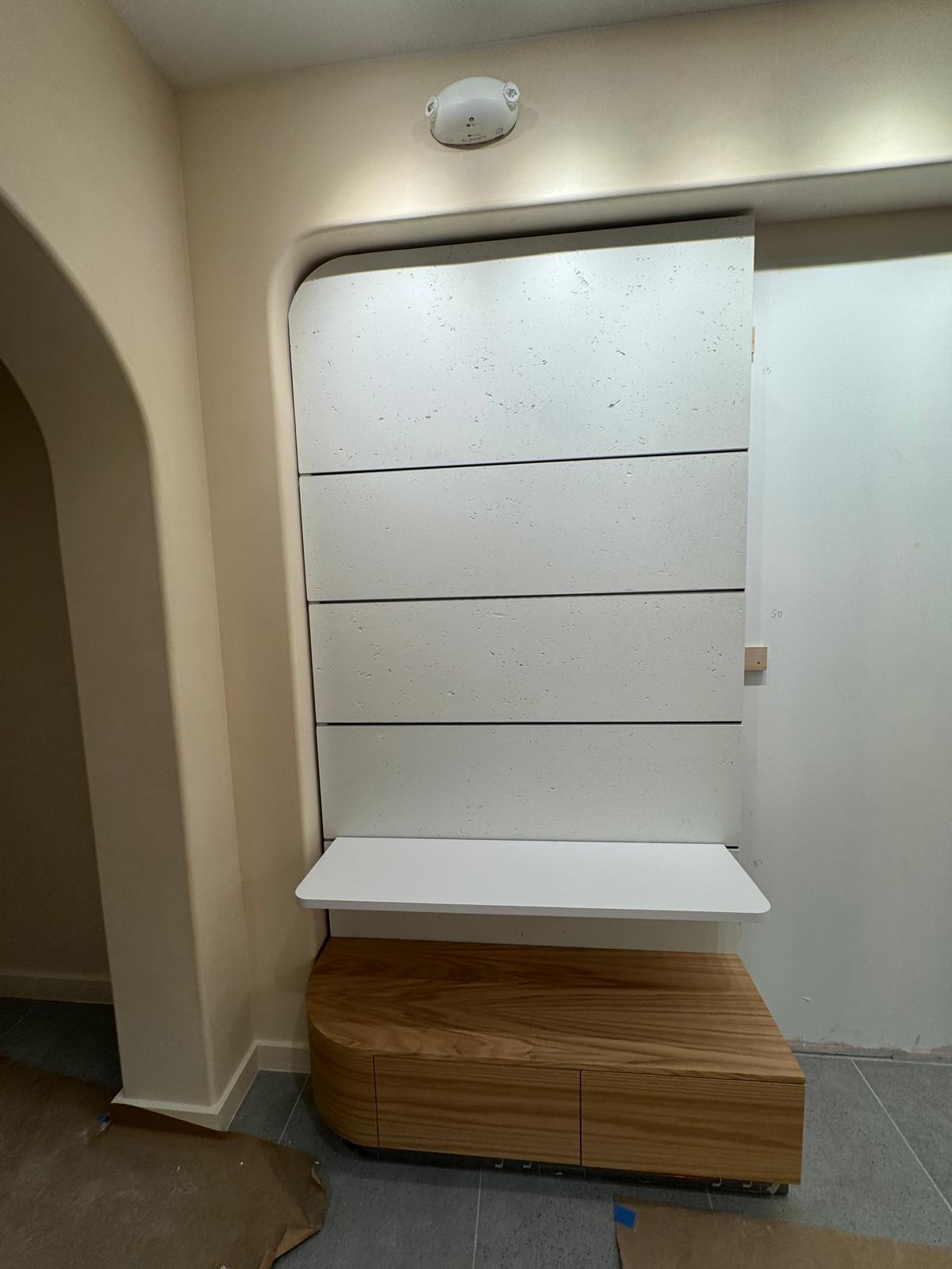 Stone-textured panel partially installed over the curved timber base.