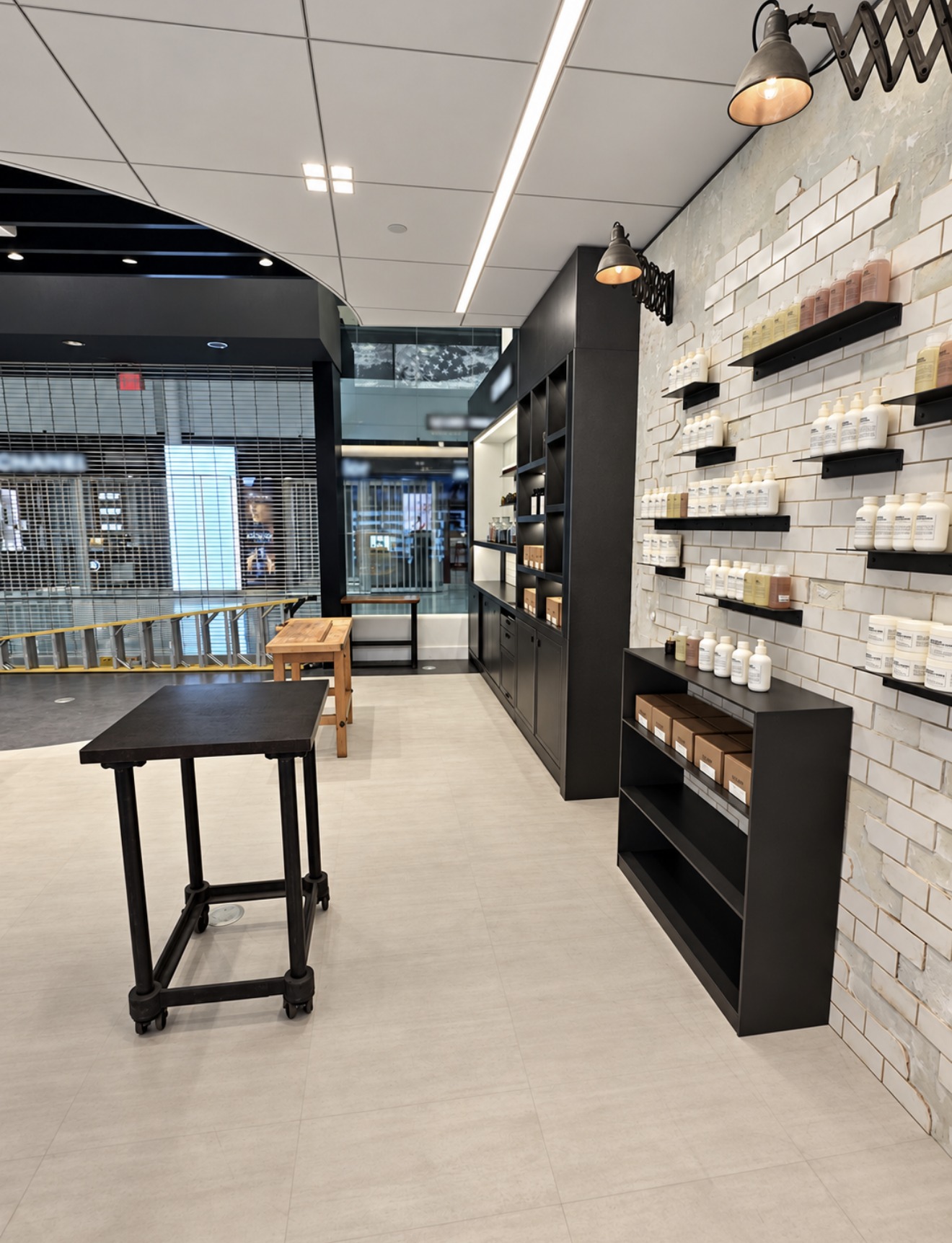Aisle view with tiled display shelf wall, product shelves and dark work table