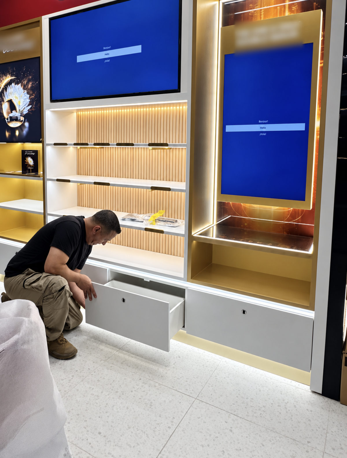 Installer opening a drawer beside illuminated shelving and blue display screens