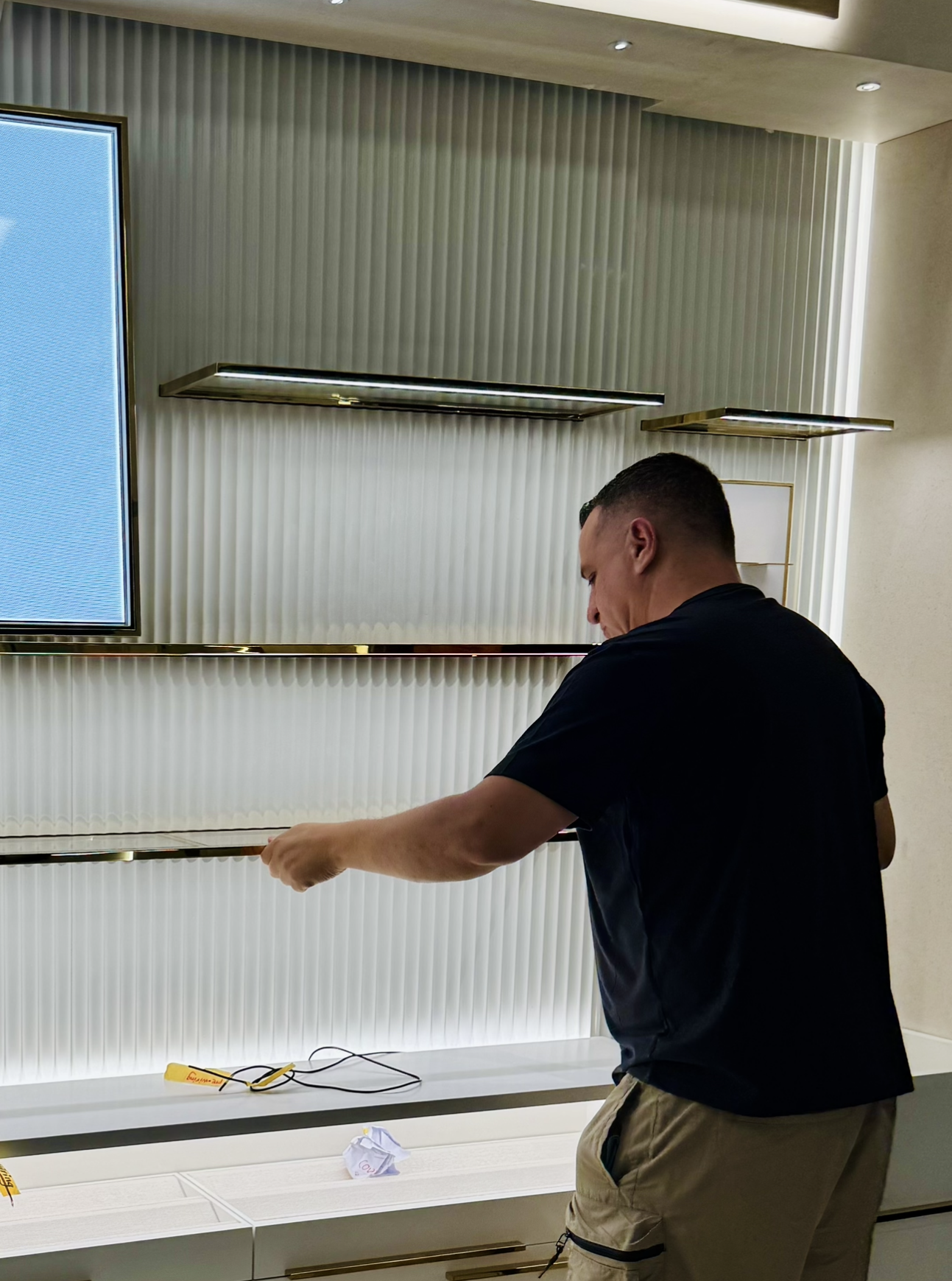 Installer precisely aligning a glass shelf with brass edging